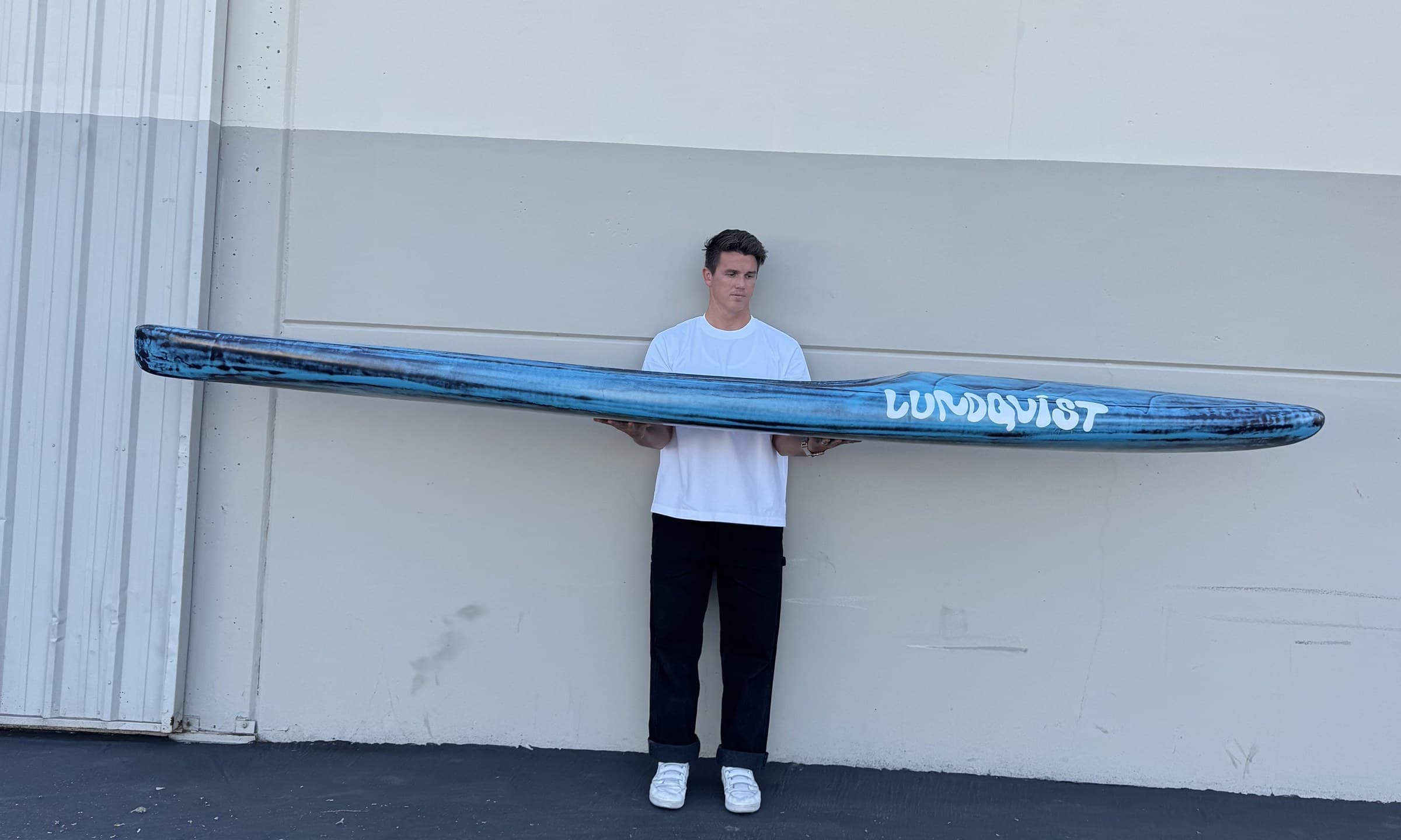 Side profile of a custom Lundquist prone paddleboard held at full length.